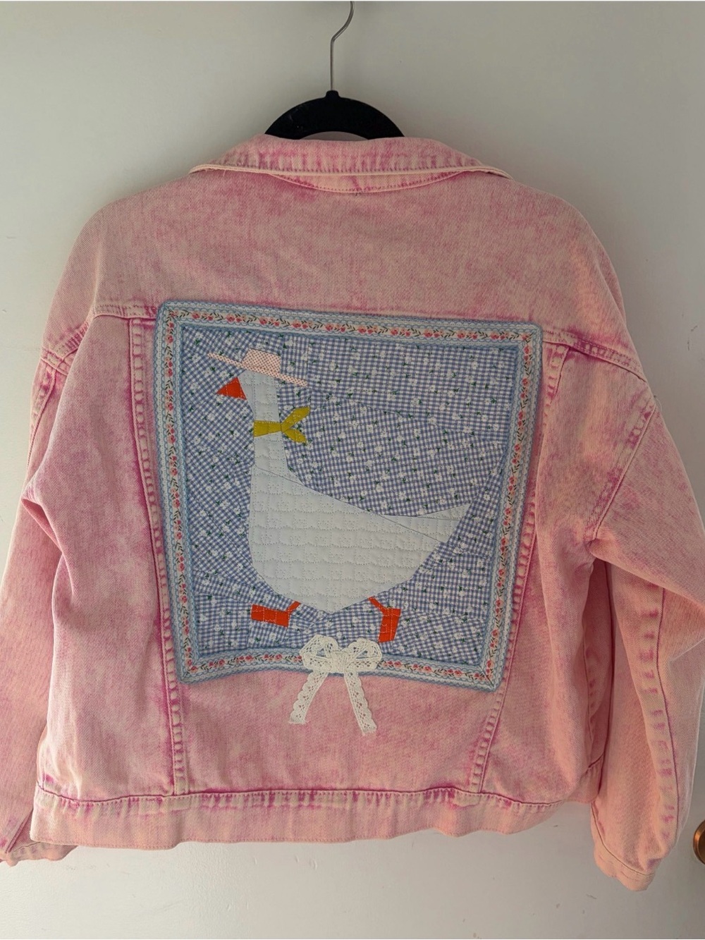 Upcycled pink Jean jacket with a quilted cowboy goose with a lace bow on the bac